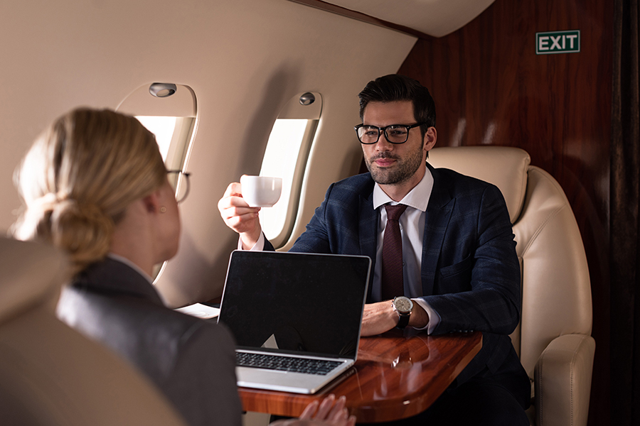 man and woman having coffee inside the private jet